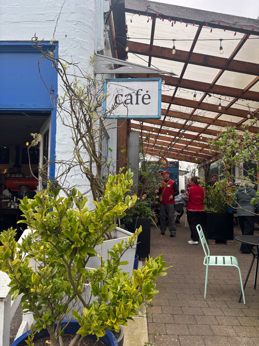 The entrance and patio of a cafe with lots of plants 