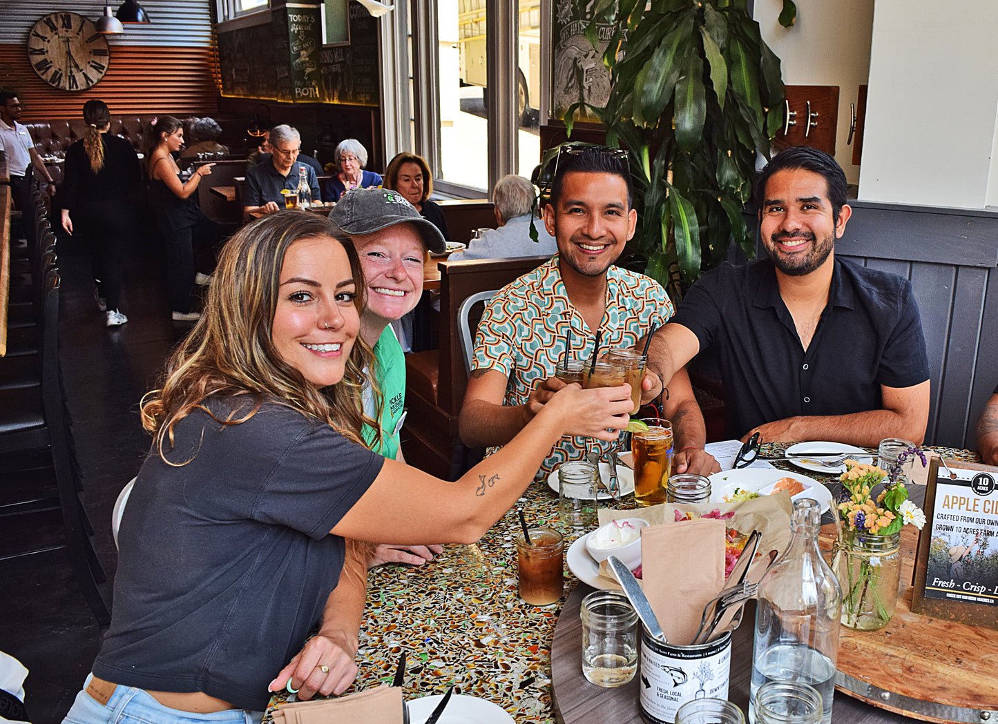 Group of people sitting at a table in a restaurant, enjoying drinks and food.