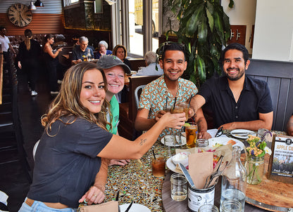 Group of people sitting at a table in a restaurant, enjoying drinks and food.