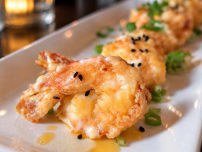 Crispy golden-brown fried shrimp skewers on a white rectangular plate, garnished with chopped green onions, black sesame seeds, and a drizzle of oil at the Bard and Banker pub